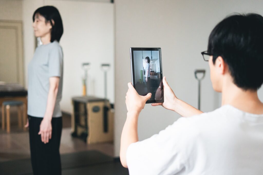 姿勢の写真を撮り、タブレットの画面で一緒に確認している様子