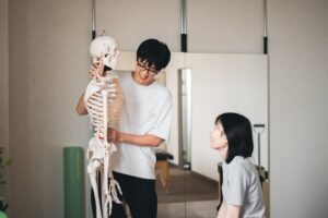 骨の模型を手に、背骨や骨盤の動きを説明している様子