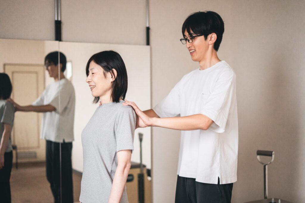 立った姿勢で、肩に手を当てて体の状態を確認している様子