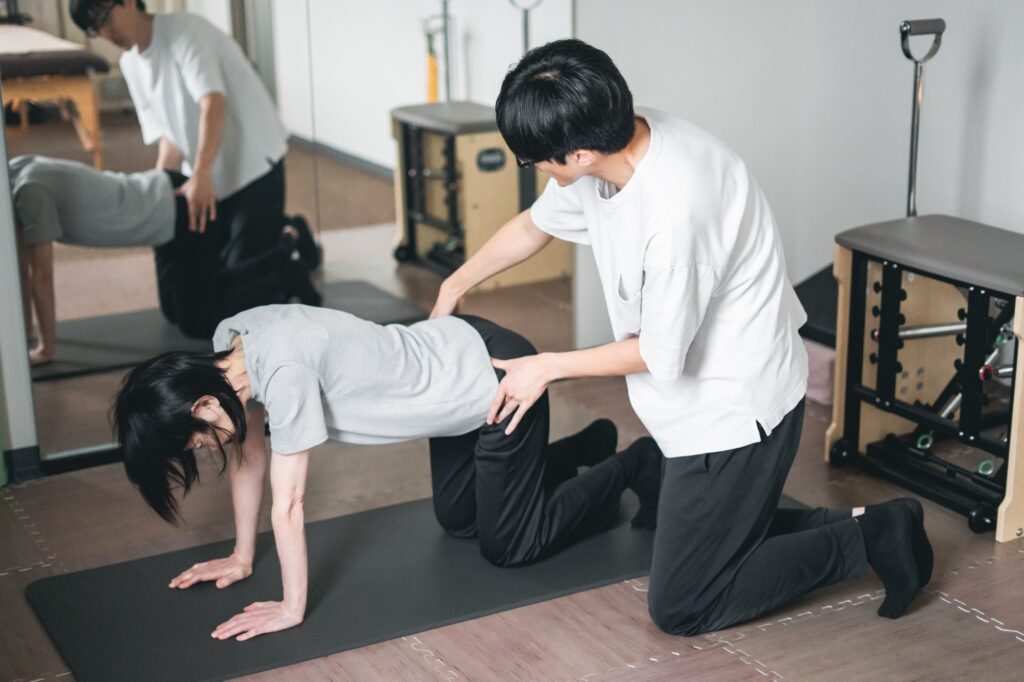 マットの上で体幹の運動を行い、院長が手を添えて動きを伝えている様子