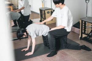 マットの上で体幹の運動を行い、院長が手を添えて動きを伝えている様子